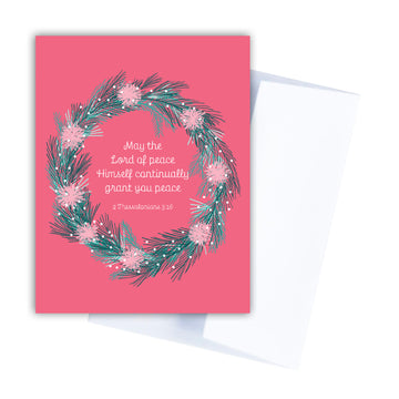 Pink Christmas card with 2 Thessalonians 3:16. May the Lord of peace Himself continually grant you peace. The Scripture is circled with an evergreen wreath.
