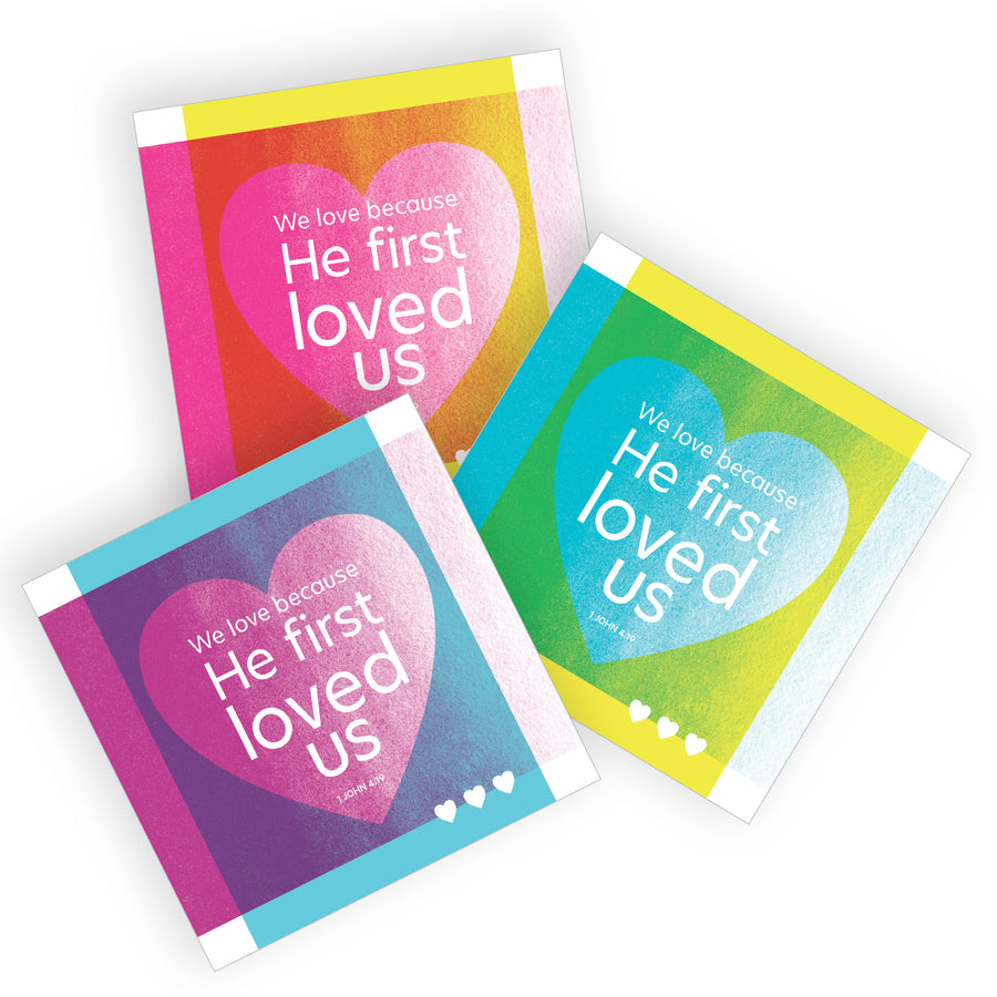 Colorful Christian mini valentine cards. Each feature a heart and the words We love because he first loved us. 1 John 4:19.  Square cards come in magenta pink and yellow, teal blue and yellow, and sky blue and warm purple.