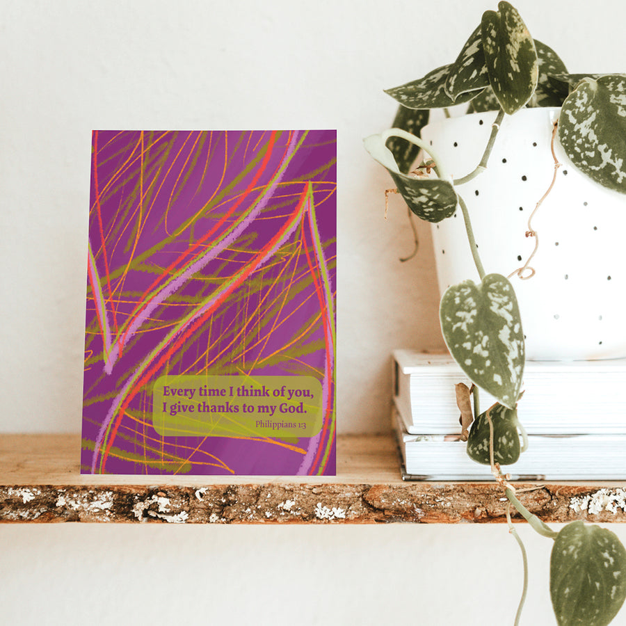 Purple Scripture greeting card with Philippians 1:3 Every time I think of you, I give thanks to my God. Card shown on wooden shelf next to potted plant.