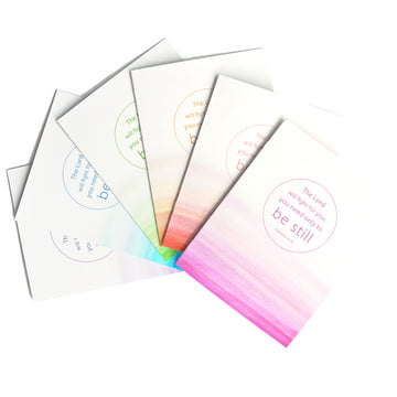 Fan of Christian greeting cards featuring Exodus 14:14 The Lord will fight for you; you only need to be still. Card features a wash of watercolor bands along the bottom. Text is in a thin ring in the center of the card; emphasis is on the phrase “be still.”