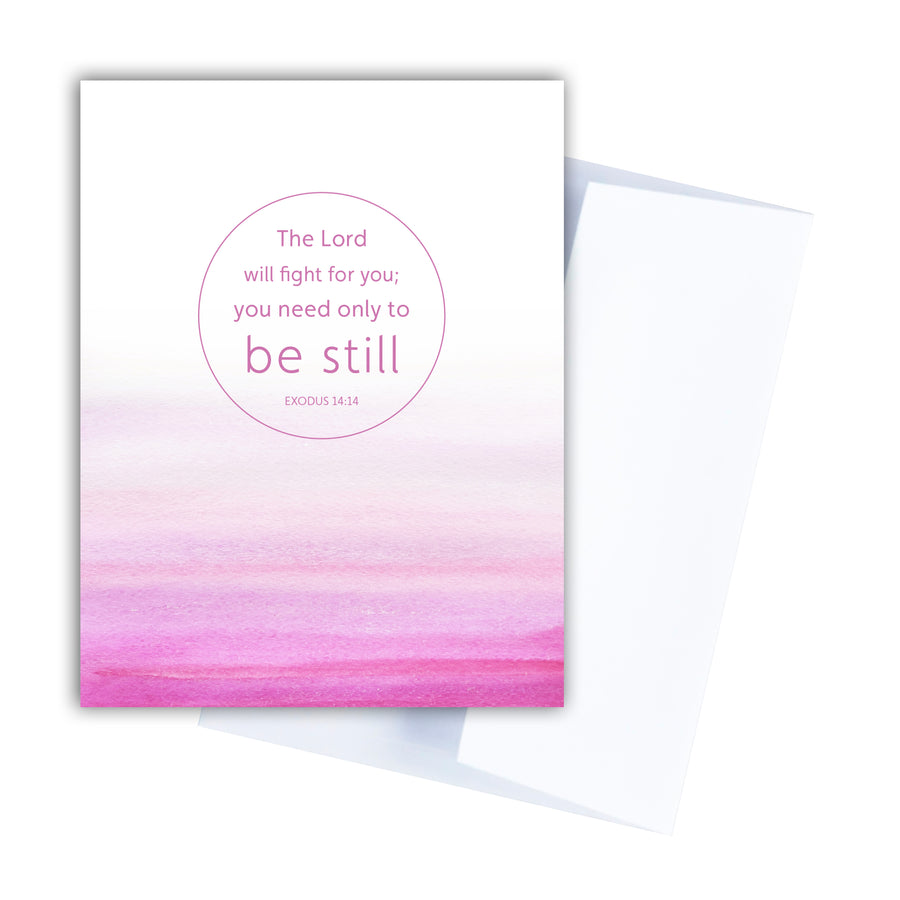 Pink Christian greeting card featuring Bible verse from Exodus 14:14 The Lord will fight for you; you only need to be still. Text is within a circle floating centered above a horizontal wash of watercolor. Blank white envelope angled behind the card.