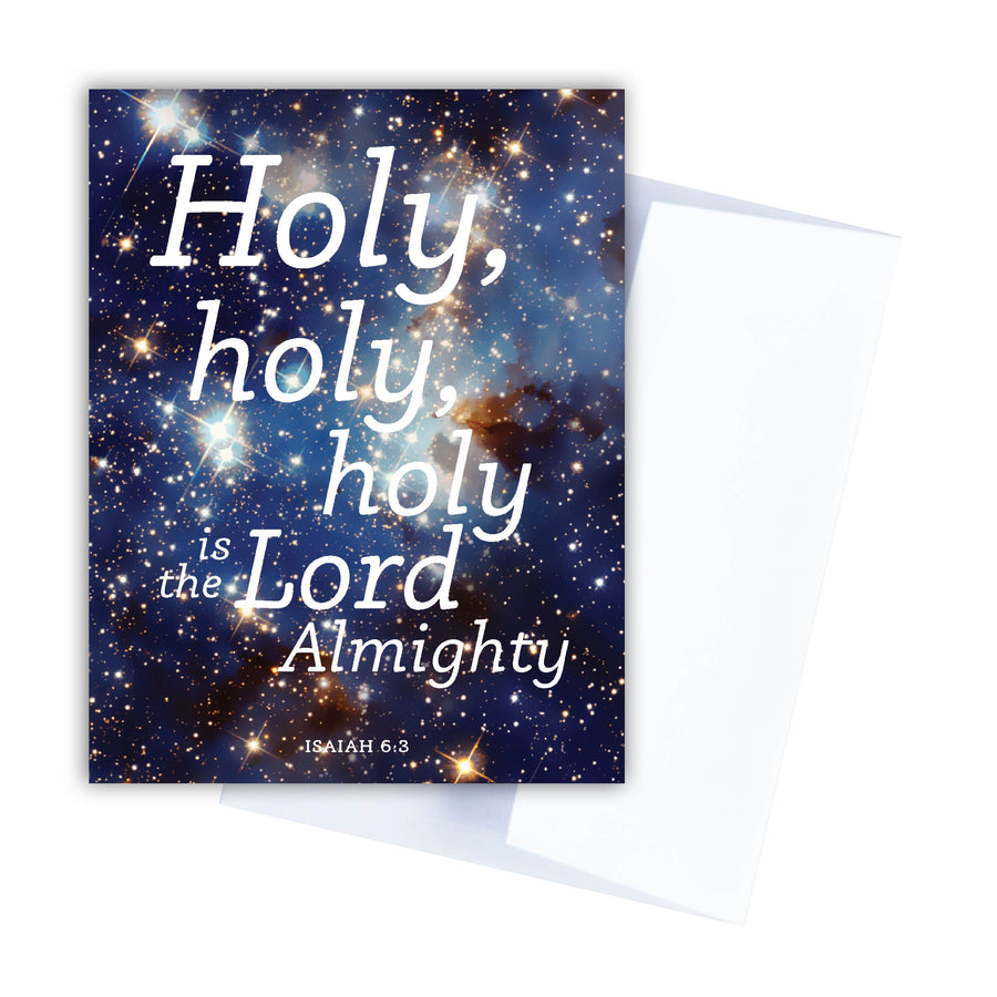 Christian holiday card with text from Isaiah 6:3 reading Holy, holy, holy is the Lord Almighty. Text is in white. Background of card features a blue photo of outer space with glowing stars. Card is shown angled over white envelope.
