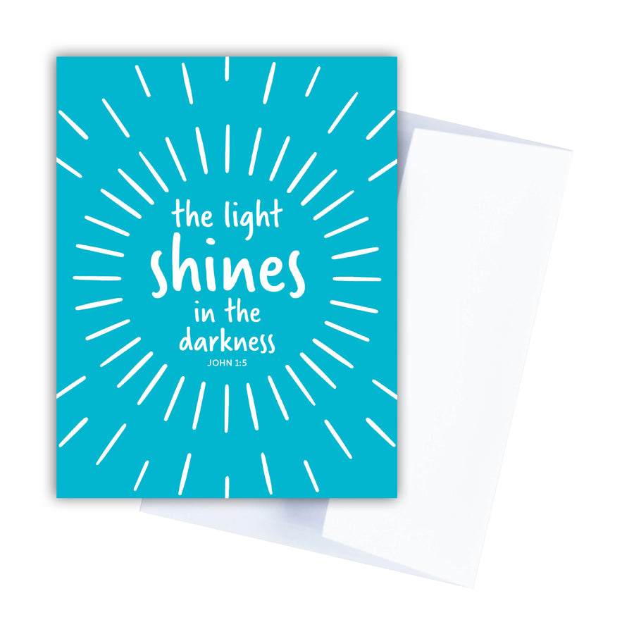 Teal Christian sympathy card with John 1:5 the light shines in the darkness. White envelope shown behind the card.