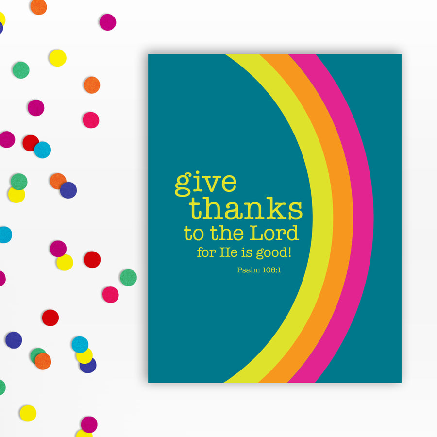 Front of a teal Bible verse greeting card with the words: give thanks to the Lord for He is good! Psalm 106:1. A curved rainbow stretches from top to bottom in hot pink, orange, and acid yellow. Confetti to the left of the card.