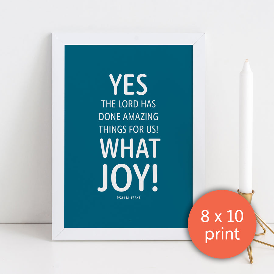 Framed Christian art print. Scripture art has peacock blue background with white text in rounded font reading Yes the Lord has done amazing things for us! What joy! Psalm 126:3. White candlestick in bronze holder to the right of framed image. Coral circle in lower right corner labels art as 8x10 print.