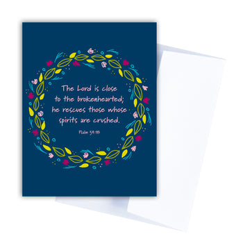 Navy blue Scripture sympathy card with words from Psalm 34:18 The Lord is close to the brokenhearted; he rescues those whose spirits are crushed. Words are circled by a wreath of leaves and flowers.