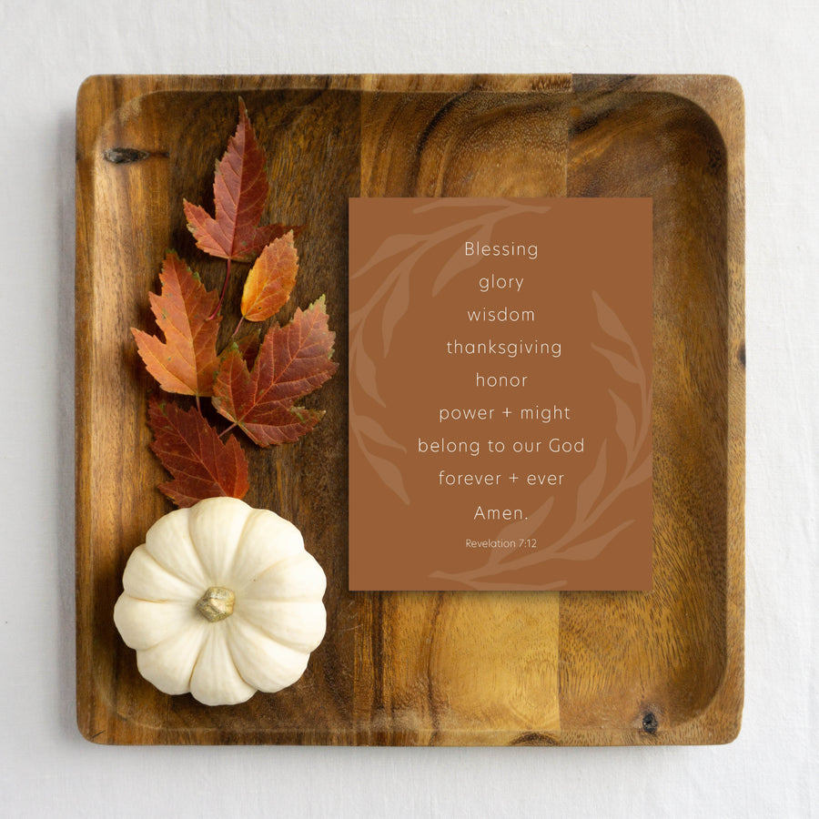 Brown Thanksgiving card with Bible verse from Revelation 7:12. Card shown on wooden tray with autumn leaves and white pumpkin.