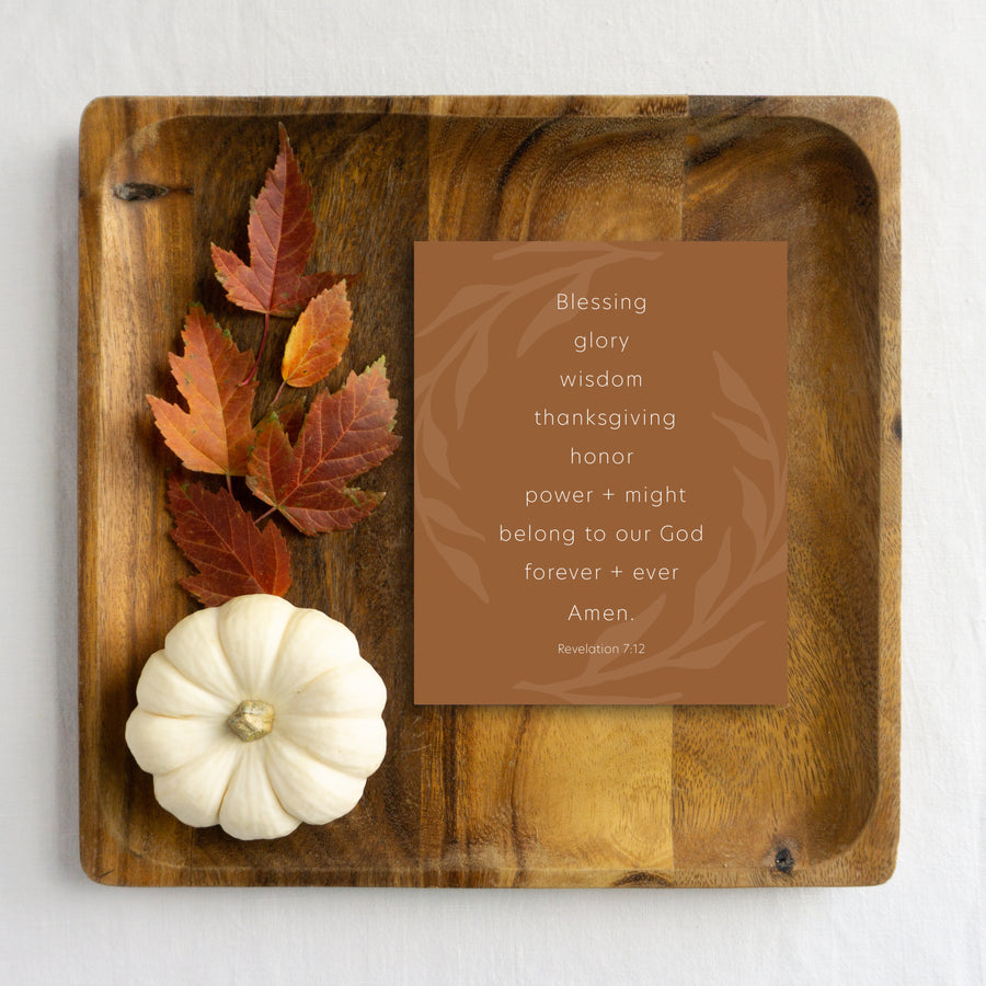 Chestnut Thanksgiving card reading Blessing, glory, wisdom, thanksgiving, honor, power and might belong to our God forever and ever. Amen. Revelation 7:12. Thanksgiving greeting card is laying on wood tray with autumn leaves and white pumpkin. 