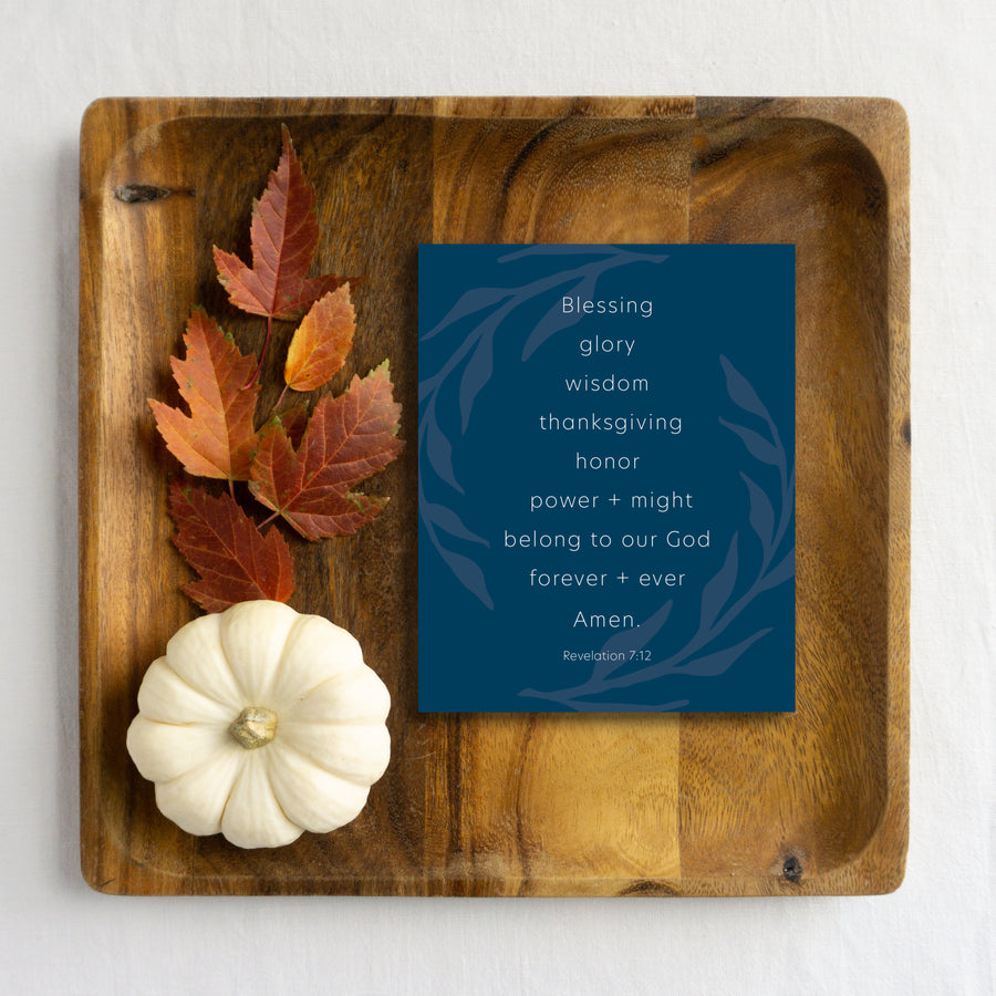 Navy blue Thanksgiving card reading Blessing, glory, wisdom, thanksgiving, honor, power and might belong to our God forever and ever. Amen. Christian Thanksgiving card is laying on wood tray with autumn leaves and white pumpkin. Revelation 7:12.