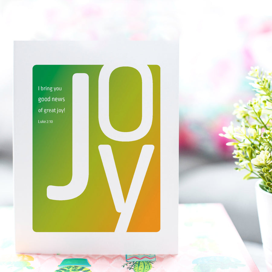 Green and orange Bible verse greeting card for new baby or adoption. Card is shown standing up on a tabletop near a houseplant.