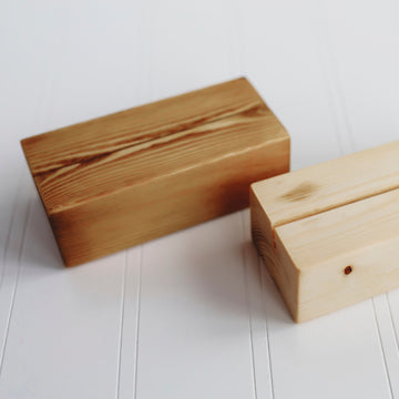 Two wood display blocks designed to display a single postcard. Each has an angled cut to allow placement of postcard. One is darker and one is lighter.